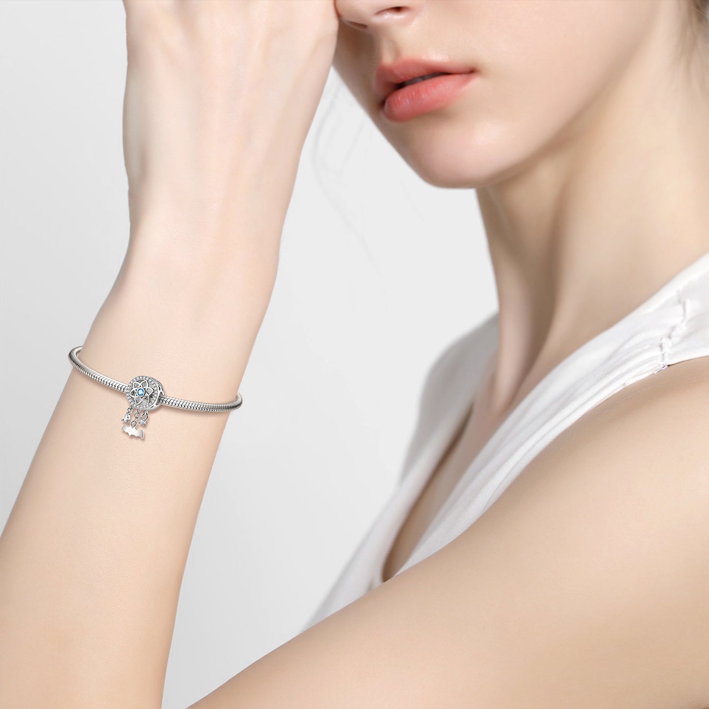 Silver bracelet with a decorative element on a person's wrist against a neutral background