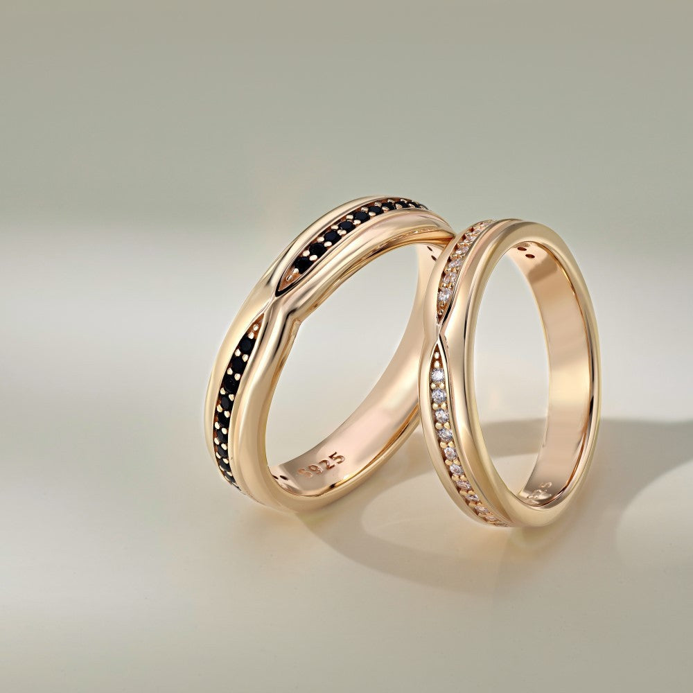 Two rose gold rings with black and white gemstones on a light green background