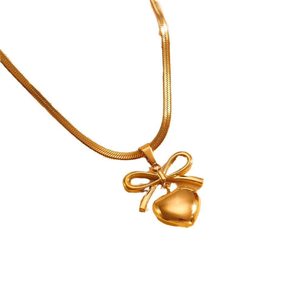 Gold necklace with a heart-shaped pendant and bow on a white background