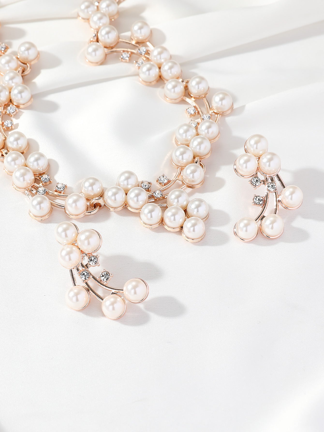 Pearl necklace with rose gold accents on a white background
