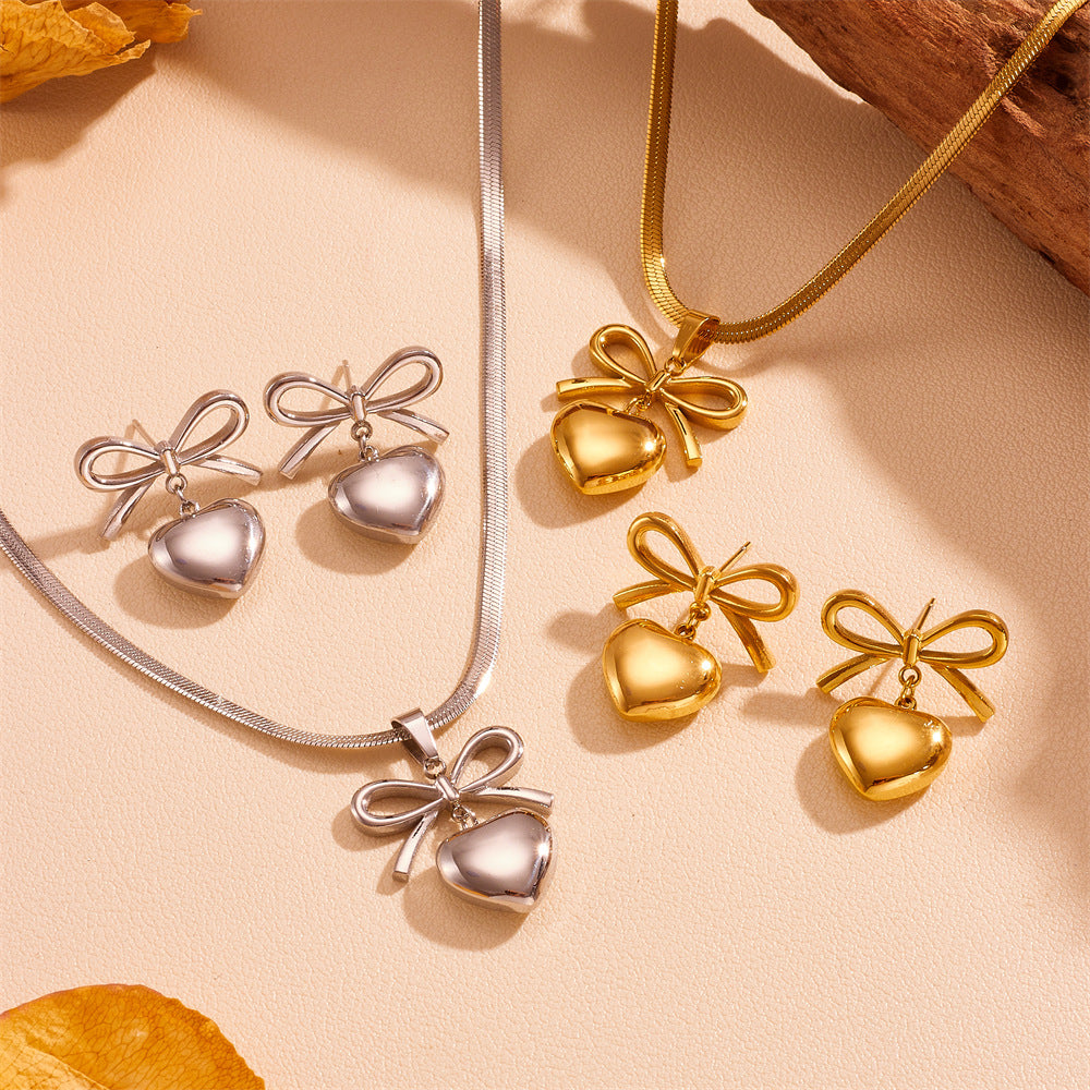 Gold and silver heart-shaped jewelry set on a beige background