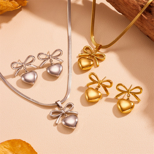 Gold and silver heart-shaped jewelry set on a beige background
