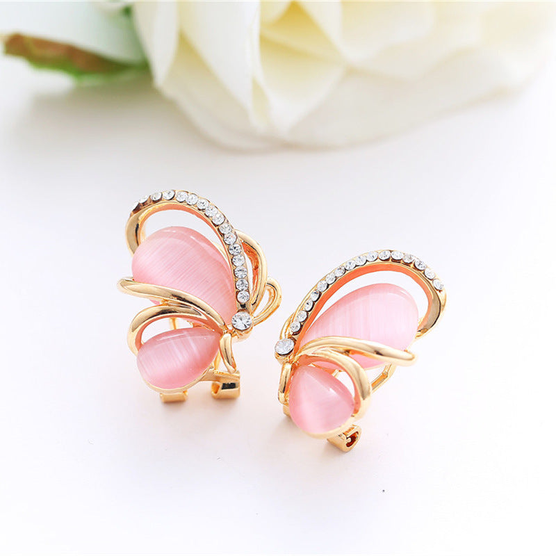 Butterfly-shaped earrings with pink centers and gold frames on a white background