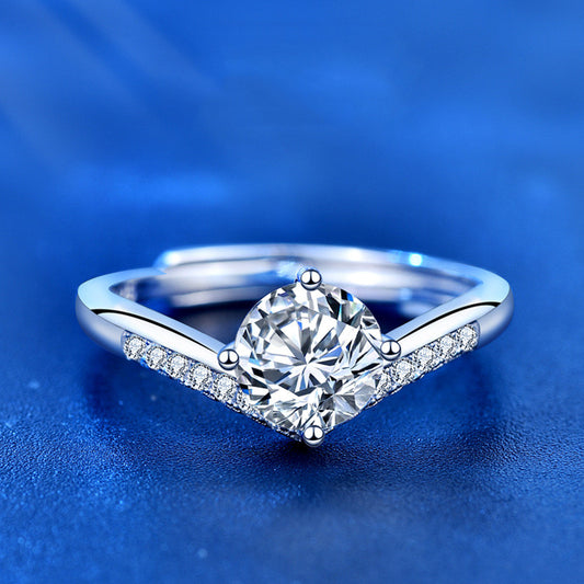 Silver ring with a large diamond and smaller diamonds on the band against a blue background