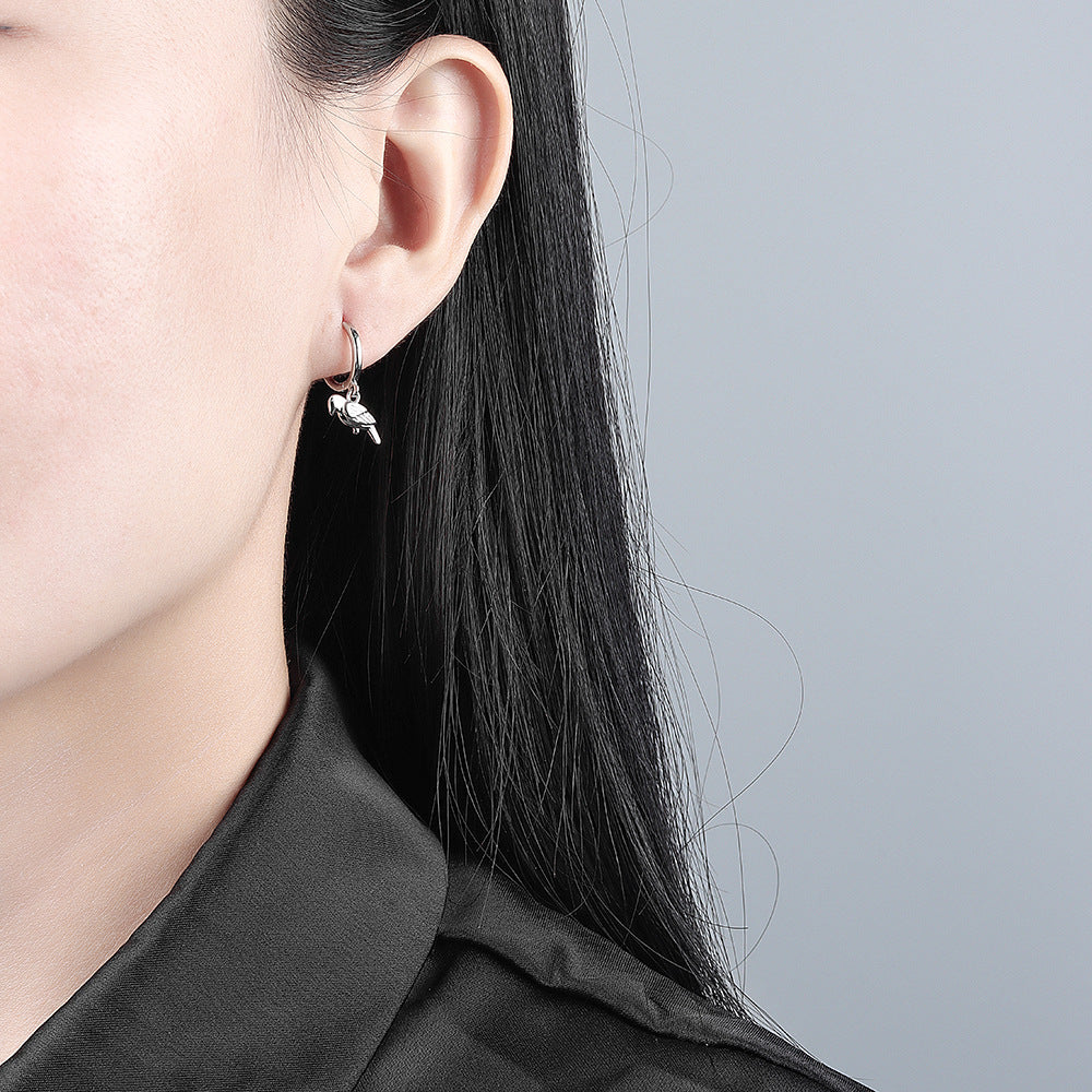 Close-up of a person wearing a silver earring with a small heart design.